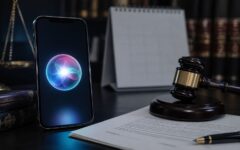 Un smartphone avec Siri posé près d’un marteau de juge et de documents juridiques